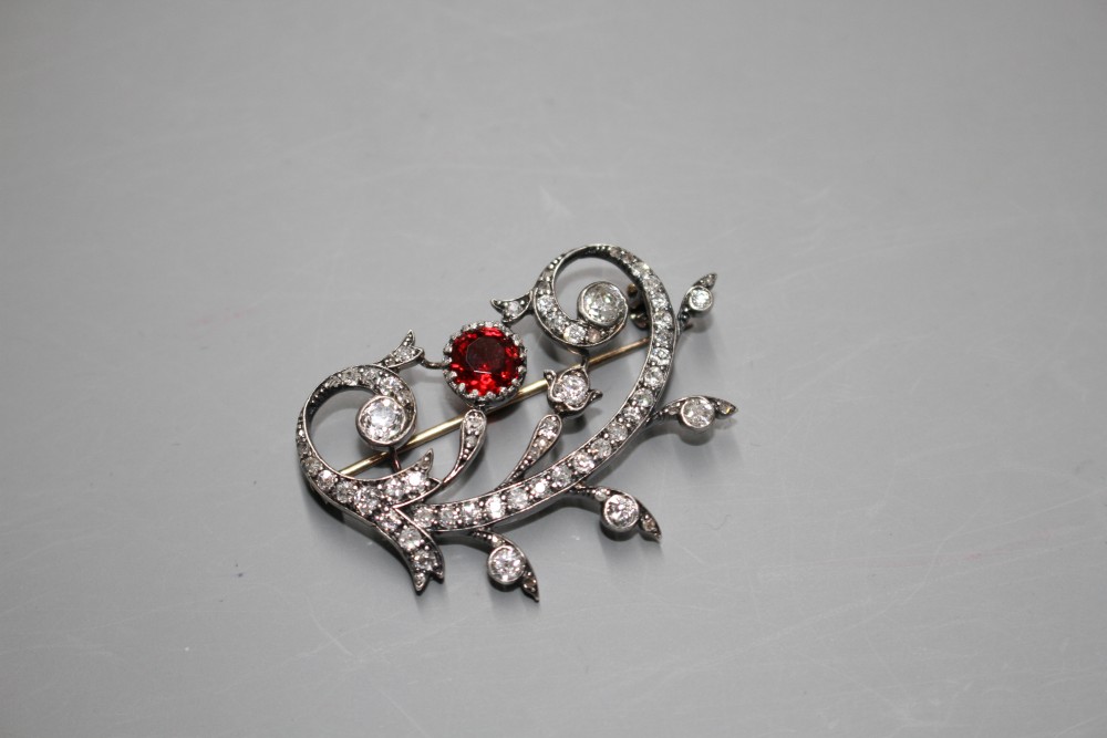 An early 20th century yellow and white metal, red spinel and diamond set foliate scroll brooch,